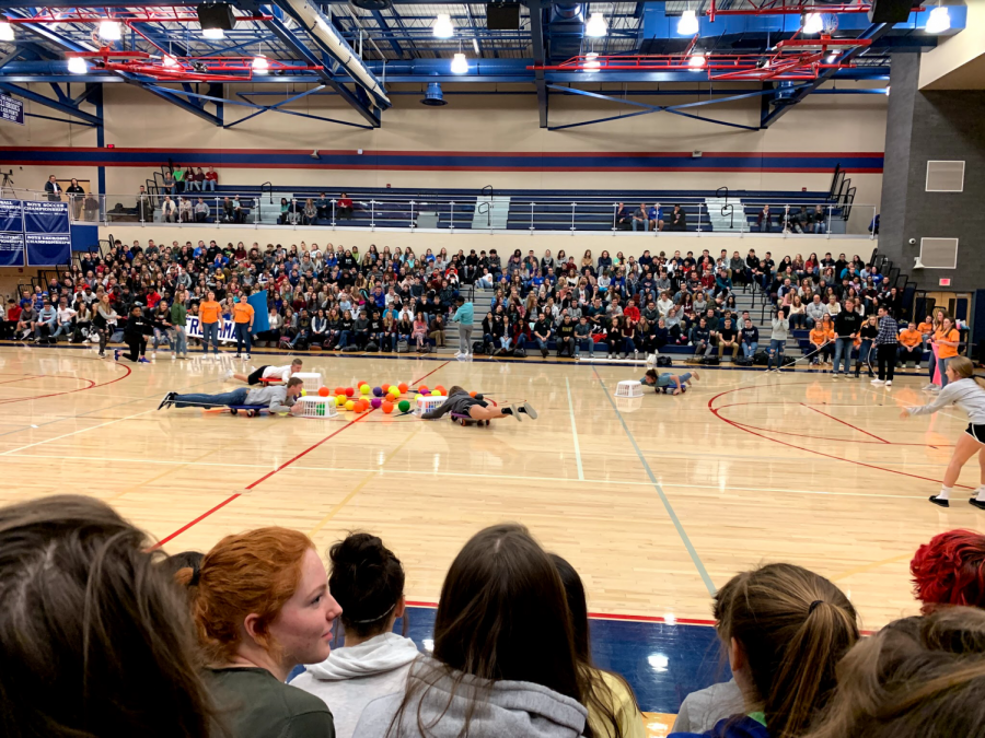All grades playing Hungry Hippo, a game where students get pushed out on scooters and try to collect as many balls as possible. 